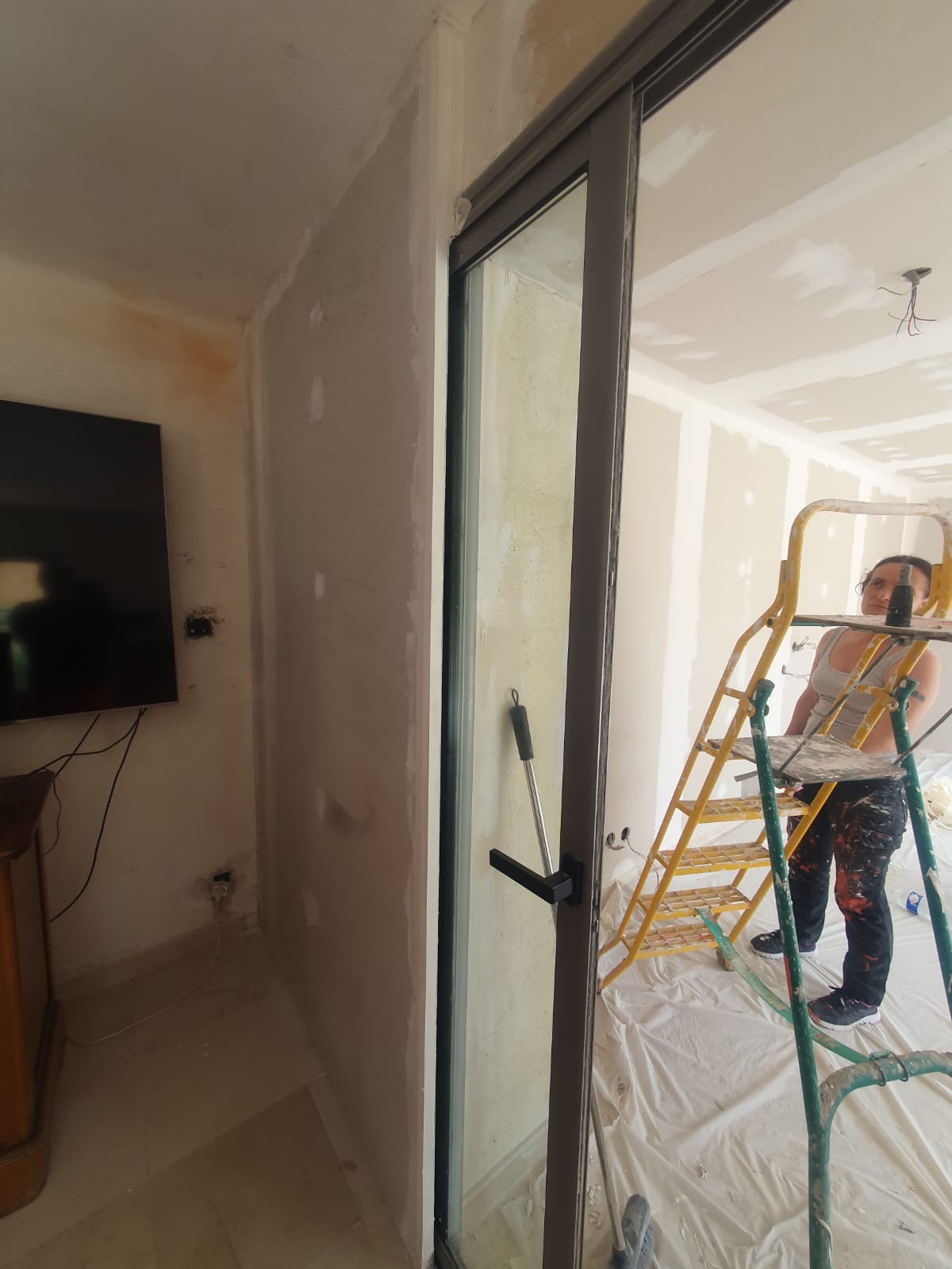 Artisan peintre au travail vu à travers une porte vitrée — rénovation intérieure