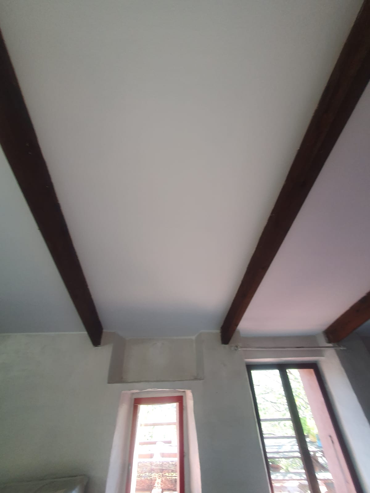 Plafond blanc peint avec poutres apparentes mises en valeur dans un mas rénové